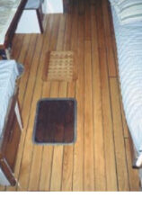 Replacing the teak cabin sole was one of Ken’s projects on his Allied Seabreeze 35 yawl, at top. He chose a cheery red oak for the conversion. When he substituted the old hatch for the newer replacement, at right center, the difference in color between the worn teak and the new oak floor covering was striking. An earlier step in that sole conversion, at right, also shows the contrast between the two woods.