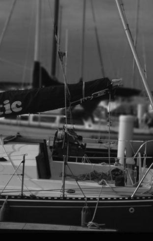 A 240-pound engine is hoisted in using the boat’s running rigging. The mainsheet tackle is connected to the main halyard, and the vang tackle pulls the engine toward the boom end. NOTHING hangs from the middle of this boom. Check the safe working load of your gear before you do this.