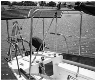 Atom’s stern showing solar panel mounts, Monitor windvane, and outboard motor.