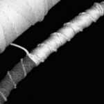 Parceling is the nautical art of wrapping a line with a long strip of heavy cloth, such as canvas or denim, as shown at the left end of this line. The parceling cushions and protects the line and makes a smoother surface for applying the serving twine.