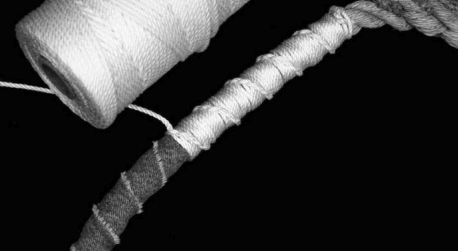 Parceling is the nautical art of wrapping a line with a long strip of heavy cloth, such as canvas or denim, as shown at the left end of this line. The parceling cushions and protects the line and makes a smoother surface for applying the serving twine.